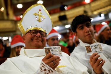 Dos personas presentes en el sorteo sostienen dos décimos con los números "0000" y "9999".