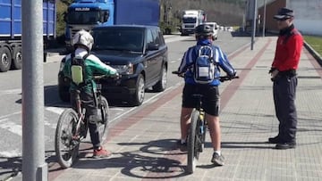 Un agente de la Polic&iacute;a Foral informa a dos ciclistas de las restricciones por el estado de alarma. 