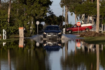 Un automóvil circula por una calle inundada después de que el huracán Milton tocara tierra en el sur de Daytona.