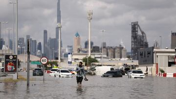A person walks in flood water caused by heavy rains, with the Burj Khalifa tower visible in the background, in Dubai, United Arab Emirates, April 17, 2024. REUTERS/Amr Alfiky