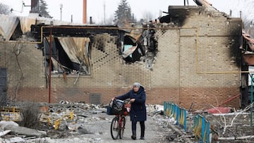 A woman walks with a bicycle next to a building damaged during Ukraine-Russia conflict in the separatist-controlled town of Volnovakha in the Donetsk region, Ukraine.