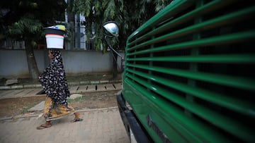 A woman carrying milk walks pass a bus parked on the street, as the government struggles to contain the spread of the coronavirus disease in Abuja, Nigeria.