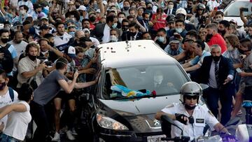 Photo released by Telam showing fans crowding next to the hearse carrying the late Argentine football legend Diego Armando Maradona while leaving Casa Rosada presidential palace to the cemetery, in Buenos Aires, on November 26, 2020. - Argentine football legend Diego Maradona will be buried Thursday on the outskirts of Buenos Aires, a spokesman said. Maradona, who died of a heart attack Wednesday at the age of 60, will be laid to rest in the Jardin de Paz cemetery, where his parents were also buried, Sebastian Sanchi told AFP. (Photo by Raul FERRARI / TELAM / AFP) / Argentina OUT / RESTRICTED TO EDITORIAL USE - MANDATORY CREDIT "AFP PHOTO / TELAM / LEANDRO BLANCO" - NO MARKETING - NO ADVERTISING CAMPAIGNS
