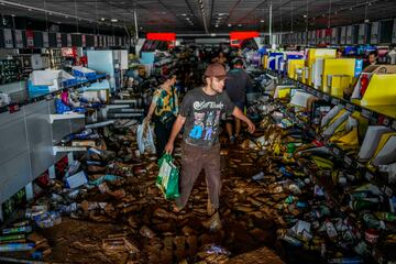 La gente recoge productos en un supermercado afectado por las inundaciones en Valencia, España.