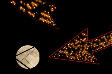 La luna se eleva tras un cartel antiguo en la cima de un edificio de apartamentos en el centro de la ciudad, el miércoles 16 de octubre de 2024, en Kansas City.