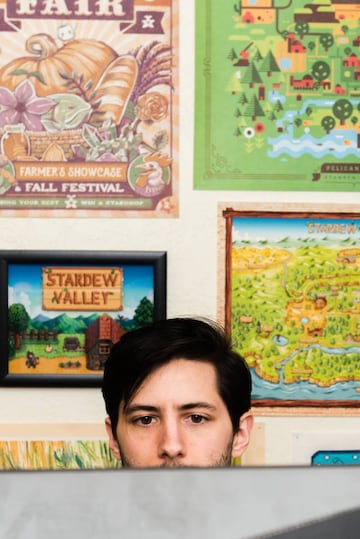 Eric Barone posa para GQ junto con varias imágenes artísticas de Stardew Valley.