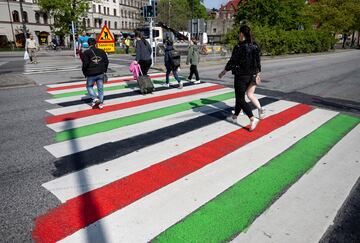 Unos viandantes cruzan un paso de peatones pintado con los colores de la bandera de Palestina.