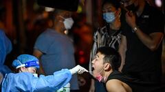 A health worker takes a swab sample from a man to test for the Covid-19 coronavirus in the Huangpu district of Shanghai, on September 20, 2022. (Photo by Hector RETAMAL / AFP) (Photo by HECTOR RETAMAL/AFP via Getty Images)