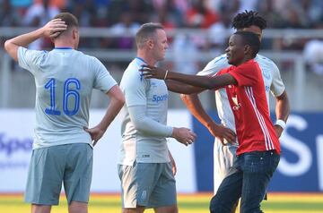 A fan runs onto the pitch to hug Everton's English striker Wayne Rooney.