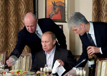 Yvgeny Prigozhin (L) assists Russian Prime Minister Vladimir Putin during a dinner with foreign scholars and journalists at the restaurant Cheval Blanc on the premises of an equestrian complex outside Moscow November 11, 2011. Picture taken November 11.  REUTERS/Misha Japaridze/Pool/File Photo