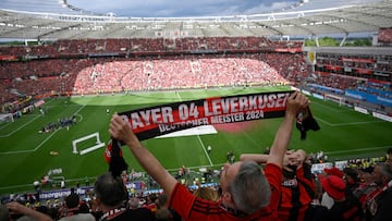 A Bayer Leverkusen fans displays a fan scarf with the lettering 'Bayer 04 Leverkusen - German champions 2024' at the BayArena Stadium in Leverkusen, western Germany on May 18, 2024, as Bayer Leverkusen's players and fans celebrate after the German first division Bundesliga football match between Bayer 04 Leverkusen and FC Augsburg. Bayer Leverkusen have become the first team in Bundesliga history to go through a season unbeaten after a 2-1 home win over Augsburg on May 18, extending their season-long run to 51 games without defeat. (Photo by Sascha Schuermann / AFP) / DFL REGULATIONS PROHIBIT ANY USE OF PHOTOGRAPHS AS IMAGE SEQUENCES AND/OR QUASI-VIDEO