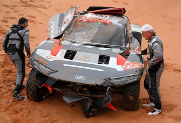 El piloto español de Audi, Carlos Sainz, y su copiloto, Luca Cruz, revisan el coche tras volcar durante la novena etapa. 