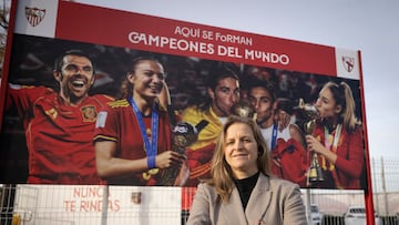 Amparo Gutiérrez, directora deportiva del Sevilla y descubridora de Olga Carmona, posa con el cartel de campeones del mundo formados en la cantera hispalense, entre los que está la lateral.