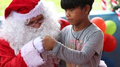 A member of the Amigos do Papai Noel (Friends of Santa Claus group) dressed in a Santa Claus costume gives a fist bump to a child during a visit to the community located along the Negro River, in Iranduba, Amazonas State, Brazil December 17, 2022. REUTERS/Bruno Kelly
