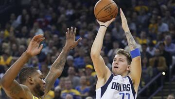Luka Doncic lanza ante Alfonzo McKinnie, de los Golden State Warriors.