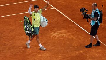 Carlos Alcaraz saluda al p¨²blico de la Philippe Chatrier despu¨¦s de ganar a Wolf en la primera ronda de Roland Garros, mientras una c¨¢mara graba su salida.
