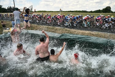 Los espectadores saludan al pelotón desde una piscina improvisada a lo largo de la ruta de la carrera, durante la 9.ª etapa de la 112.ª edición del Tour de Francia, 174,1 km entre Chinon y Chateauroux, en el centro de Francia, el 13 de julio de 2025.