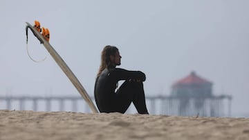 Huntington Beach (United States), 01/05/2020.- A surfer sits on the sand at Huntington Beach, California, USA, 01 May 2020. California Governor Gavin Newsom ordered the closing of California beaches to avoid the spread of the COVID-19 disease caused by th
