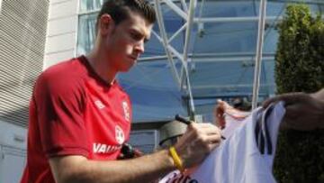 Gareth Bale firma una camiseta del Real Madrid.