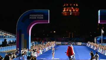 The first runner of the "Marathon Pour Tous" (Marathon For All) crosses the finish line as the dome of the Hotel des Invalides is seen in the background in Paris on August 10, 2024, on the sidelines of the Paris 2024 Olympic Games. (Photo by Loic VENANCE / AFP)