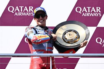 Marc Márquez posa en el podio, sonriente, con el trofeo que le acredita como vencedor de la carrera del GP de Australia 2024.
