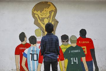 Solo falta un día para que dé comienzo el Mundial de Qatar 2022 y la fiesta del fútbol ya se vive en cada rincón del planeta, incluso en Bangladesh. En la imagen, un niño mira un graffiti dibujado en una calle de Dhaka, en el que aparecen algunos de los mejores jugadores del mundo observando el trofeo de la Copa Mundial de fútbol. 