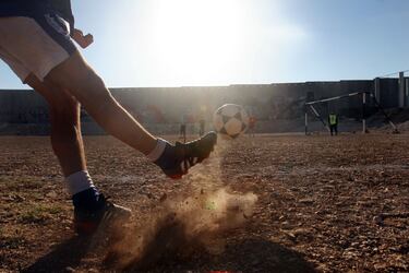 Jóvenes palestinos juegan al fútbol junto a un tramo de la barrera de separación israelí, en la aldea cisjordana de Abu Dis, a las afueras de Jerusalén.