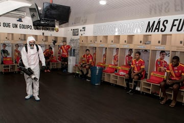 Una empleado desinfecta el vestuario del Sport Herediano mientras los jugadores esperan sentados. Los clubes profesionales de fútbol de Costa Rica volvieron a los entrenamientos tras más de un mes de confinamiento por el coronavirus.