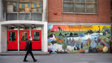 A man wearing a protective mask walks past P.S. 87 William Sherman School during the outbreak of the coronavirus disease (COVID-19) in the Manhattan borough of New York City, New York, U.S., April 12, 2020. REUTERS/Jeenah Moon