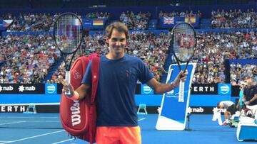 Roger Federer levanta sus raquetas para saludar, delante del númeroso público que fue a verle entrenarse.
