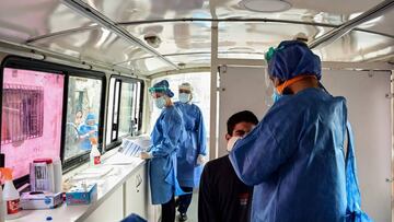 An Argentine dentist, who graduated from the University of Buenos Aires (UBA), works as a volunteer collecting a sample for a COVID-19 test from a man to detect cases of the COVID-19 coronavirus, in La Boca neighborhood, Buenos Aires, on August 3, 2020. - A group of volunteers of the University of Buenos Aires (UBA) is dedicated to look for coronavirus-infected people in guesthouses, nursing homes and among police forces to alleviate doctors from this task so they can concentrate in treatments. (Photo by RONALDO SCHEMIDT / AFP)
