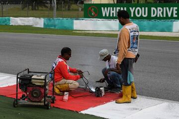 Los operarios del circuito de Sepang arreglan la alcantarilla que provocó el accidente del piloto francés.