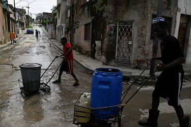 La gente lleva agua potable en bidones y contenedores plásticos antes de la llegada del huracán Melissa, en Santiago de Cuba