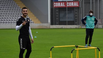 Un jugador de Nacional de Madeira, junto a un miembro del cuerpo t&eacute;cnico con mascarilla, durante la vuelta al trabajo en el estadio.