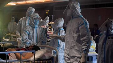 Health workers wearing personal protective equipment (PPE kit) attends to Covid-19 coronavirus positive patients inside a banquet hall temporarily converted into a covid care centre in New Delhi on April 29, 2021. (Photo by TAUSEEF MUSTAFA / AFP)