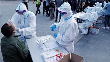 A medical worker in protective suit collects a swab from a resident at a makeshift nucleic acid testing site, following cases of the coronavirus disease (COVID-19) in Shanghai, China March 11, 2022. Picture taken March 11, 2022. cnsphoto via REUTERS ATTENTION EDITORS - THIS IMAGE WAS PROVIDED BY A THIRD PARTY. CHINA OUT.