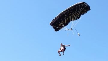 El saltador Arne Haugland soltando su paraca&iacute;das y lanz&aacute;ndose, visto desde el agua de un lago. 