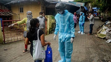 A volunteer health worker of the Non-Governmental Organization (NGO) Bharatiya Jain Sanghatana (BJS) wearing Personal Protective Equipment (PPE) using a smart helmet equipped with a thermo-scan sensor checks the body temperature of residents during a door