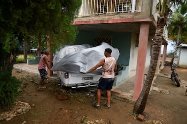 Hombres cubren un automóvil para protegerlo del huracán Melissa mientras la tormenta avanza hacia Cuba, tras tocar tierra en Jamaica, en Santiago de Cuba, Cuba.