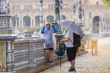 Viandantes protegiéndose de la lluvia en la Plaza de España de Sevilla.