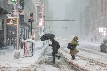 Los peatones caminan por una calle mientras cae nieve durante una tormenta invernal en la ciudad de Nueva York.