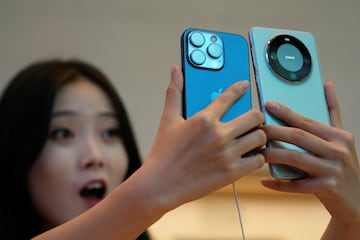 A woman looks at a new iPhone 15 Pro and a Huawei Mate 60 Pro as Apple's new iPhone 15 officially goes on sale across China, at an Apple store in Shanghai, China September 22, 2023. REUTERS/Aly Song