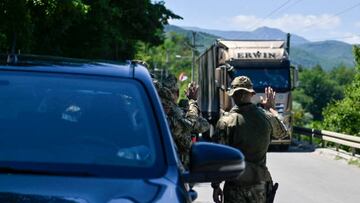 NATO soldiers greet a truck driver near the town of Zubin Potok on August 1, 2022. - Serbs in North Kosovo removed barricades on August 1 that closed two crossings along the border with Serbia after authorities in Pristina postponed the implementation of new travel measures that sparked tensions. Trucks and barriers were being cleared from the roads, according to an AFP reporter, hours after a string of shootings and air raid sirens in northern Kosovo sent tensions soaring in the disputed territory home to both Serbs and ethnic Albanians. (Photo by Armend NIMANI / AFP) (Photo by ARMEND NIMANI/AFP via Getty Images)