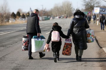 Carrying what little they can take with them, a mother and her two children walk towards the Ukrainian border with Hungary at Beregsurany.