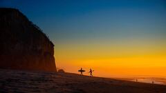 Dos surfistas en la playa que salen del agua al atardecer tras una sesi&oacute;n de surf en Portugal.