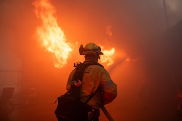 Un bombero lucha contra el incendio de Palisades mientras arde durante una tormenta de viento en el lado oeste de Los Ángeles.