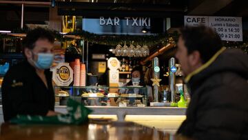 Dos clientes conversan mientras una camarera sirve platos de comida en un establecimiento de Vitoria (Euskadi/Espa&ntilde;a) a 12 de diciembre de 2020.