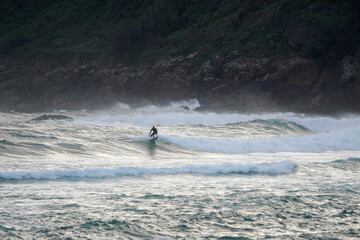 Un surfista coge una ola en la Zurriola tras permitirse a los adultos que puedan realizar ejercicio por primera vez en siete semanas, dentro del plan de desescalada por fases aprobado pro el Gobierno. 