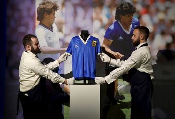 Trabajadores de la casa de subastas inglesa Sotheby¡¯s posan con la camiseta que Maradona utiliz¨® en el partido de cuartos de final del Mundial 86 contra Inglaterra, en el que el astro argentino marc¨® los dos goles (2-1), los conocidos como La Mano de Dios y El Gol del Siglo. La estimaci¨®n supera los 4 millones de libras esterlinas.