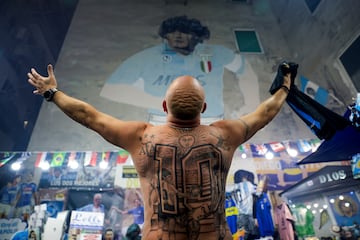 Se cumplieron cuatro años de la muerte de Diego Armando Maradona, pero los hinchas argentinos y napolitanos siguen teniendo muy presente a su gran ídolo. En la imagen, un aficionado con un gran tatuaje del 10 en su espalda muestra su admiración ante un mural del mito argentino en los Quartieri Spagnoli, templo de Maradona en Nápoles.